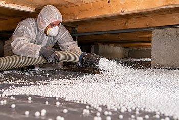 Kruipruimte isoleren met EPS-parels als bodemisolatie Monteur brengt EPS-parels aan als bodemisolatie in de kruipruimte onder een houten vloer